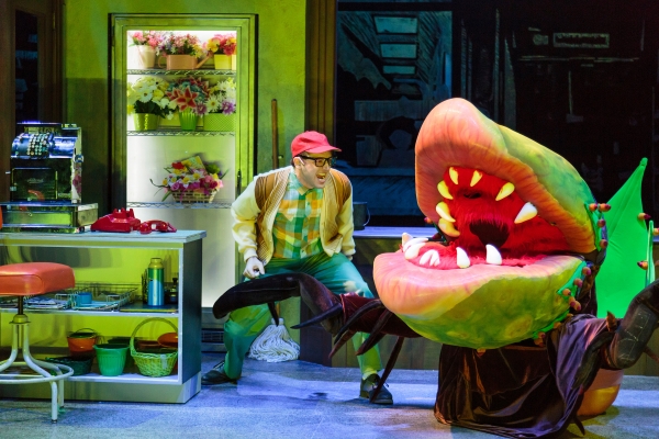 Seymour (Joshua Carter) and the Audrey II (puppeteer: Eric Esteb, voice: Ekello Harrid Jr.) in Little Shop of Horrors, a co-production of ACT and The 5th Avenue Theatre.   Credit: Tracy Martin